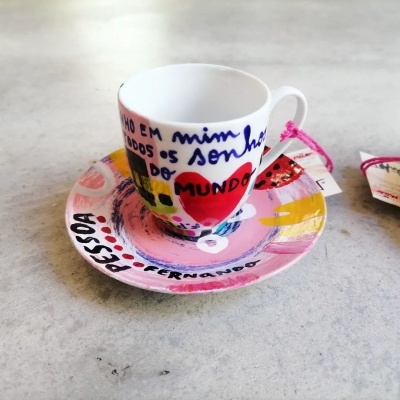 Chávena de café com pires coloridos e texto pintado à mão