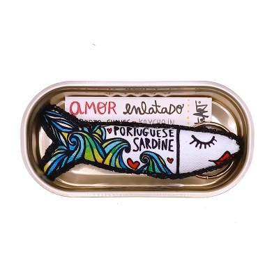 Sardinha de peluche colorida numa lata de conserva dorada com etiqueta com texto português