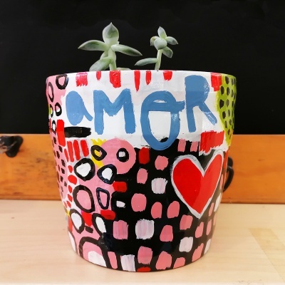 Vaso de cerâmica colorido com padrões e texto AMOR, com suculentas verdes