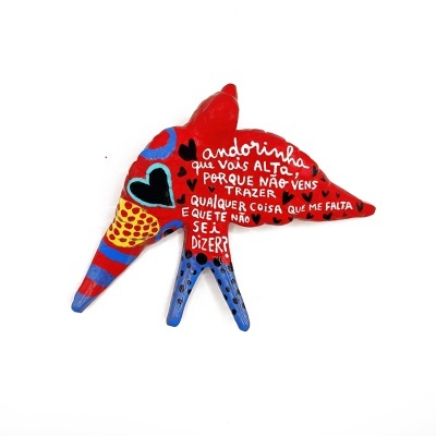 Escultura colorida de andorinha com texto em português na asa direita