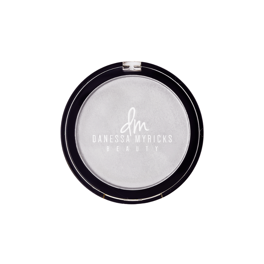 Dew Wet Balm Danessa Myricks Beauty Pó compacto Danessa Myricks Beauty em embalagem preta redonda com tampa transparente.