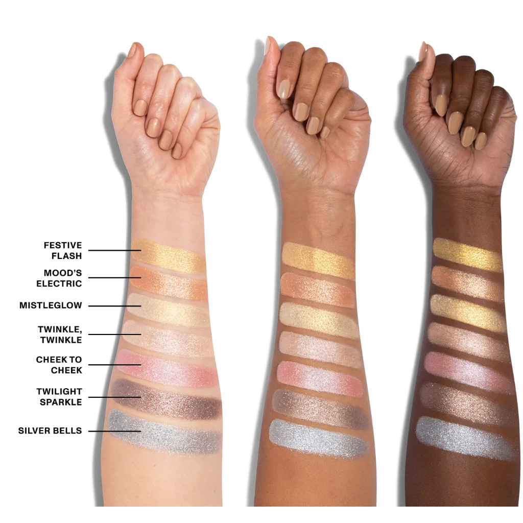 Paleta de Sombras 35XS No Silent Nights Artistry Morphe Três braços com diferentes tons de pele exibindo amostras de maquilhagem em faixas horizontais coloridas e brilhantes com nomes ao lado.