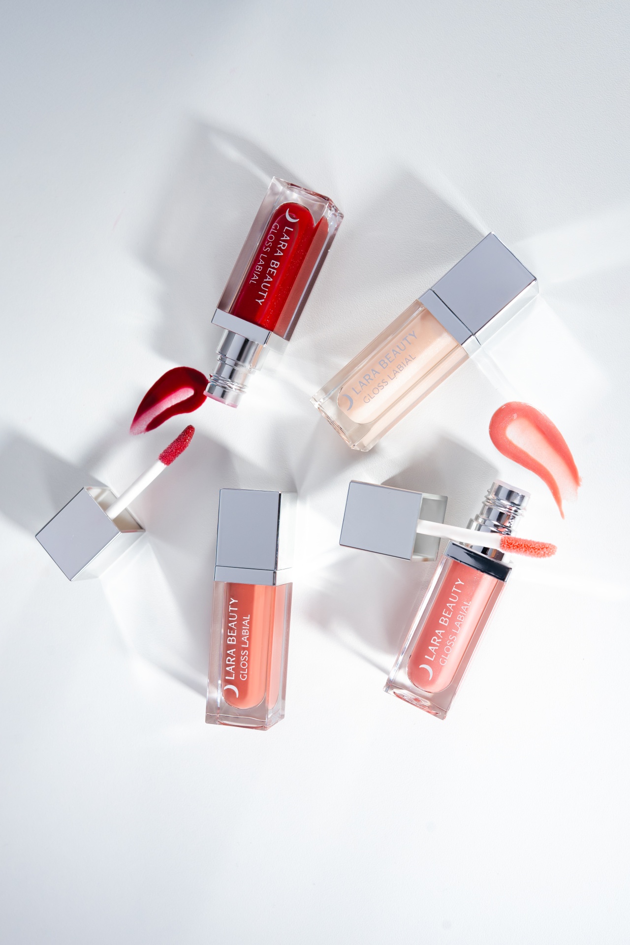 Gloss Lara Beauty Quatro gloss labial LARA BEAUTY em várias cores com amostras em fundo branco