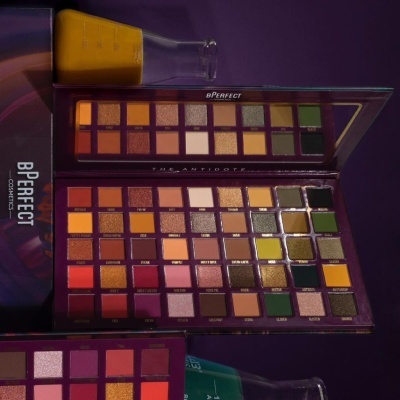 Paleta de sombras BPerfect The Antidote com várias cores e embalagem roxa sobre superfície escura.