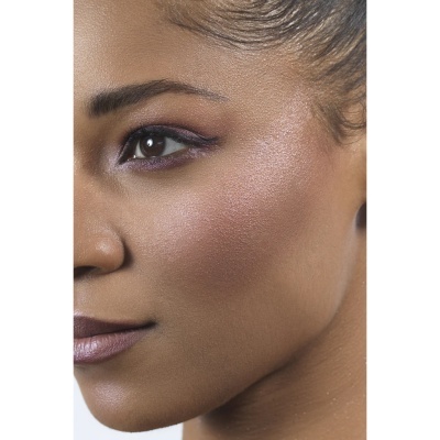 Close-up do rosto de uma mulher com maquilhagem roxa e pele luminosa