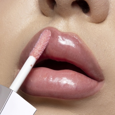 Lábios com gloss labial rosa sendo aplicado por aplicador branco felpudo