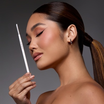 Mulher com pincel branco de maquilhagem LARA BEAUTY perto do rosto em fundo cinza