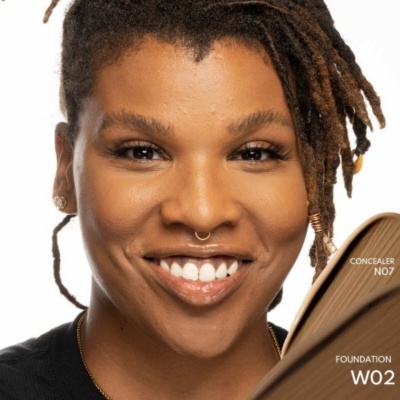 Pessoa a sorrir com dreadlocks e amostras de maquilhagem castanha