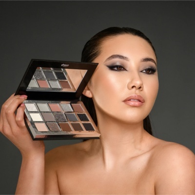 Paleta de sombras de olhos várias cores com espelho, segurada por mulher com maquilhagem.