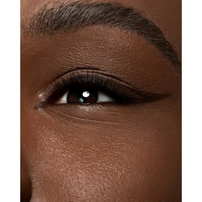 Close-up de um olho castanho escuro com pele castanha e maquilhagem discreta