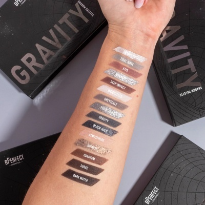 Braço com amostras de sombras de olhos e embalagens pretas da paleta GRAVITY