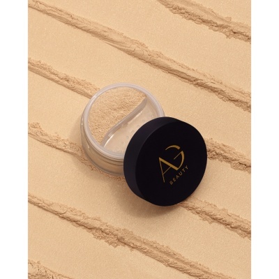 Pó solto de maquilhagem bege com embalagem transparente e tampa preta AG BEAUTY