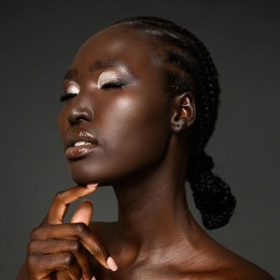 Mulher negra com maquilhagem dourada e cabelo em tranças num coque