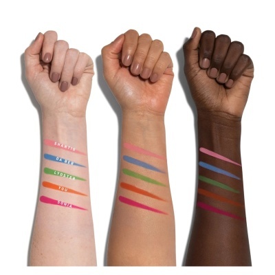 Três braços com diferentes tons de pele e linhas coloridas de maquilhagem visíveis no antebraço.