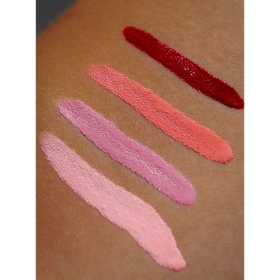 Quatro amostras de batom líquido em diferentes tonalidades de rosa, coral e vermelho num braço.