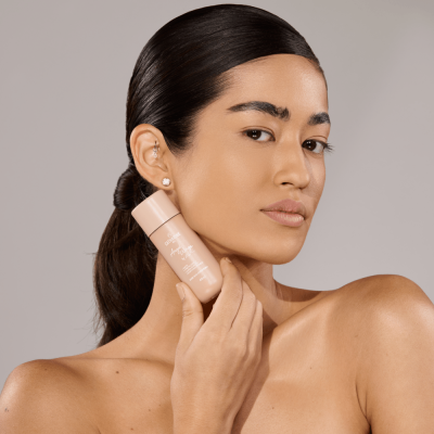 Mulher segurando frasco de cosmético bege claro