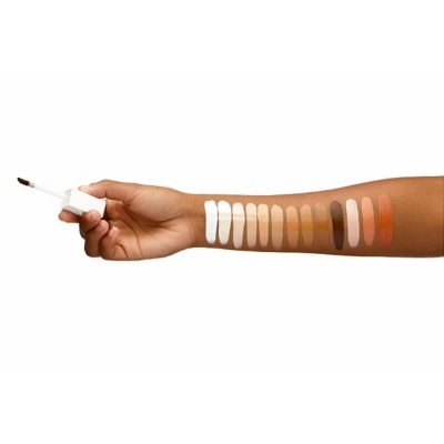 Braço com amostras de maquilhagem em várias cores e aplicador de pincel.