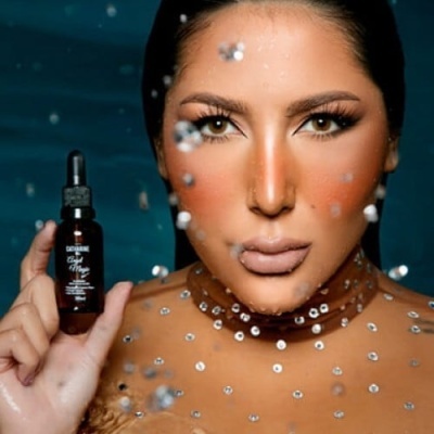 Mulher a segurar frasco com conta-gotas e bolhas de água em fundo azul escuro