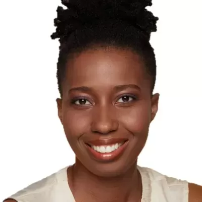 Rosto de mulher negra sorridente com cabelo afro preso e blusa bege