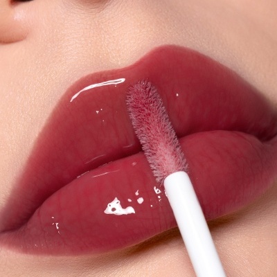 Lábios com batom gloss rosa brilhante sendo aplicado