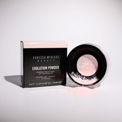 Pó compacto Danessa Myricks Beauty Evolution Powder com caixa preta e branca num fundo branco