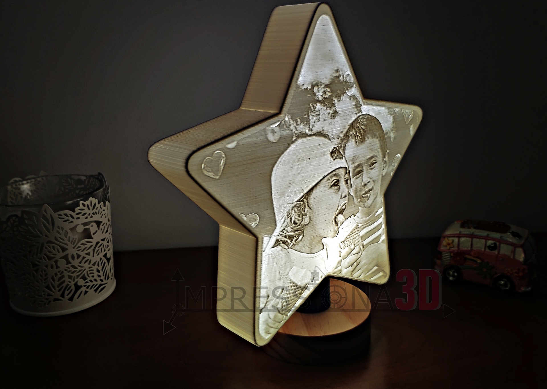 Lâmpada em forma de estrela com foto de crianças, base preta, copo decorativo e miniatura de carrinha ao fundo