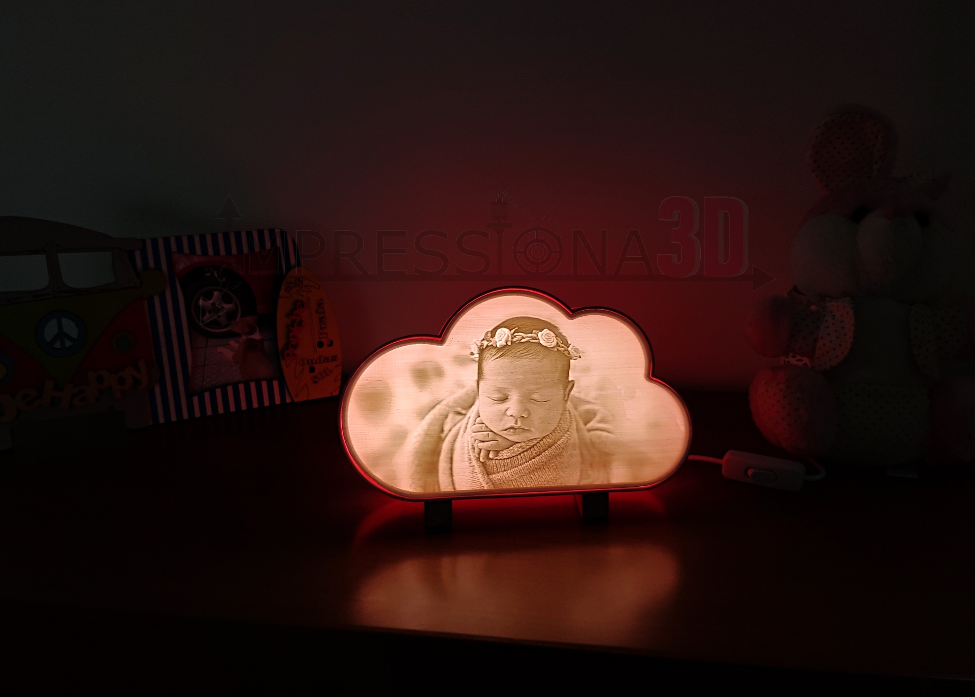 Luminária em forma de nuvem com foto de bebé e luz vermelha num ambiente escuro