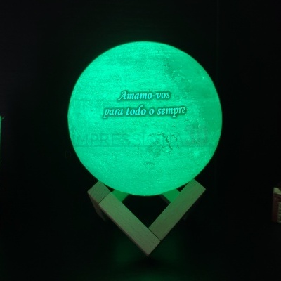Globo iluminado verde com texto e base de madeira entre objetos decorativos