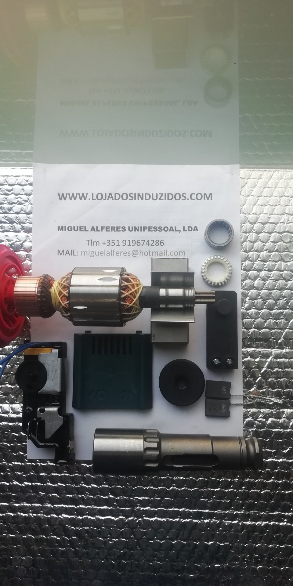 INDUZIDO P/ BOSCH GSH11E Peças mecânicas e documento com contacto de empresa sobre superfície texturizada prateada.