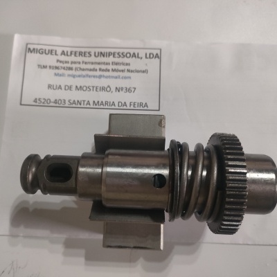 Peça mecânica metálica com mola e roda dentada junto a cartão de visita em fundo branco