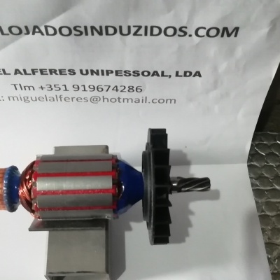 Rotor de motor elétrico com enrolamentos de cobre e ventilador, sobre tecido prateado e papel com texto informativo