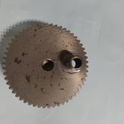 Engrenagem metálica bronze com orifícios centrais sobre fundo branco