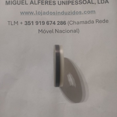 Objeto circular preto com bordas prateadas sobre papel com texto impresso e contactos
