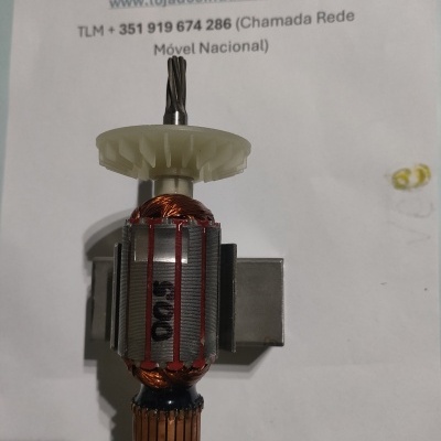 Peça elétrica com eixo, engrenagem branca e enrolamento de cobre sobre papel com texto