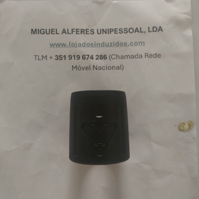 Objeto preto com símbolo triangular sobre papel com texto de contacto da empresa