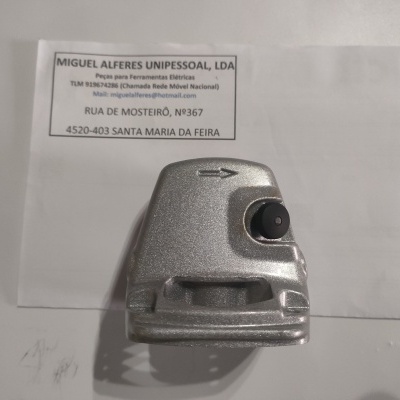 Objeto metálico prateado com botão preto e uma seta gravada, sobre papel com texto da empresa Miguel Alferes Unipessoal