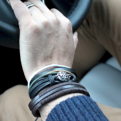 Pulseiras masculinas de couro castanho e preto no pulso de uma pessoa