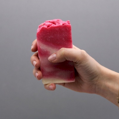 Barra de sabonete artesanal rosa e branca na mão