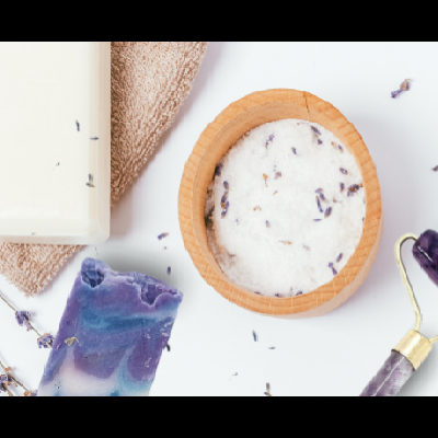 Produtos de spa: garrafa branca, toalha castanha, sal grosso, rolo de quartzo roxo e sabão roxo e branco