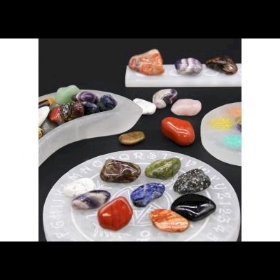 Várias pedras polidas coloridas sobre suportes brancos com letras e números, fundo preto