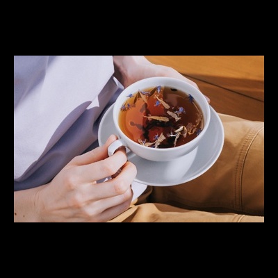 Pessoa a segurar chávena branca de chá com flores e folhas