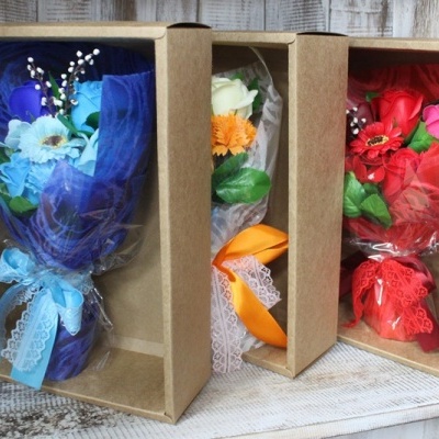 Três bouquets de flores artificiais embalados em caixas de cartão com fitas coloridas