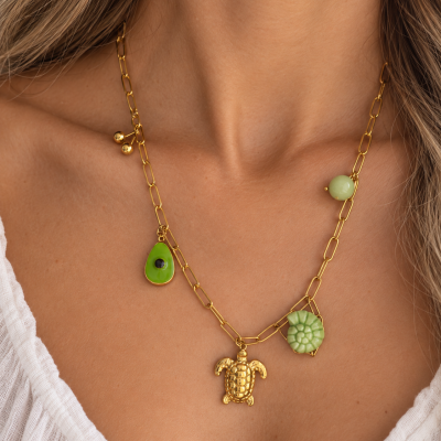 Colar dourado com pendentes verdes e tartaruga em pescoço de mulher