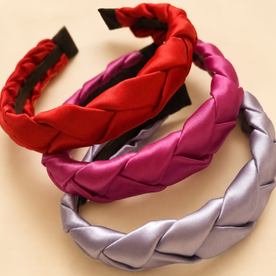 Três tiaras de cabelo trançadas em tecido acetinado nas cores vermelho, rosa e lilás