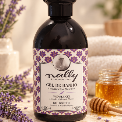 Frasco preto de gel de banho com rótulo roxo e creme e texto, ramo de lavanda e pote de mel