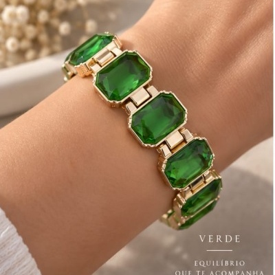 Pulseira dourada com pedras verdes retangulares em pulso