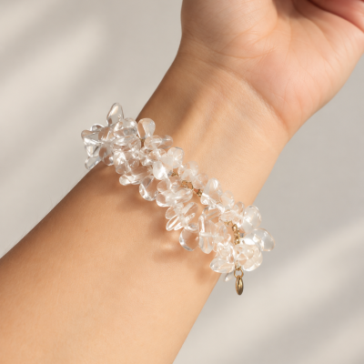 Pulseira de cristais transparentes com corrente dourada no pulso