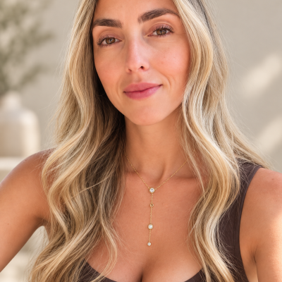 Colar em ouro com três pedras brillantes num pescoço feminino