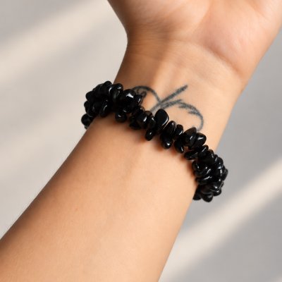 Pulseira preta de pedras irregulares no pulso com tatuagem de borboleta