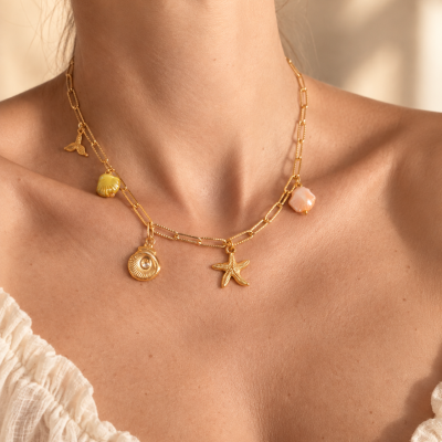 Colar dourado com pendentes de concha e estrela do mar no pescoço de mulher